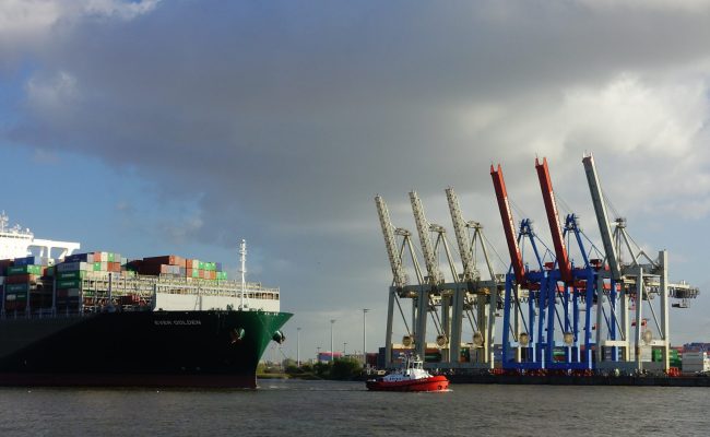 big containership let by a tug boat in hamburg harbor